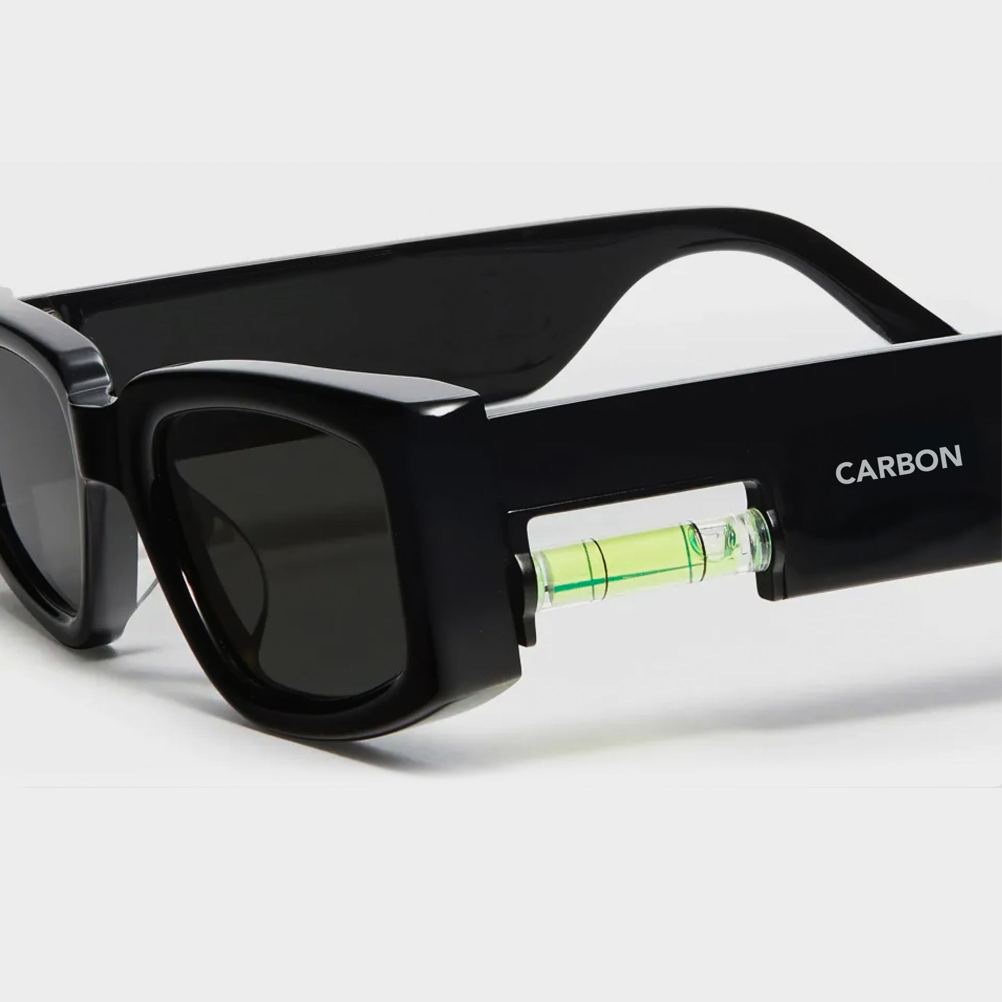 Black sunglasses with a level inside on a white background, featuring the brand 'Carbon'.