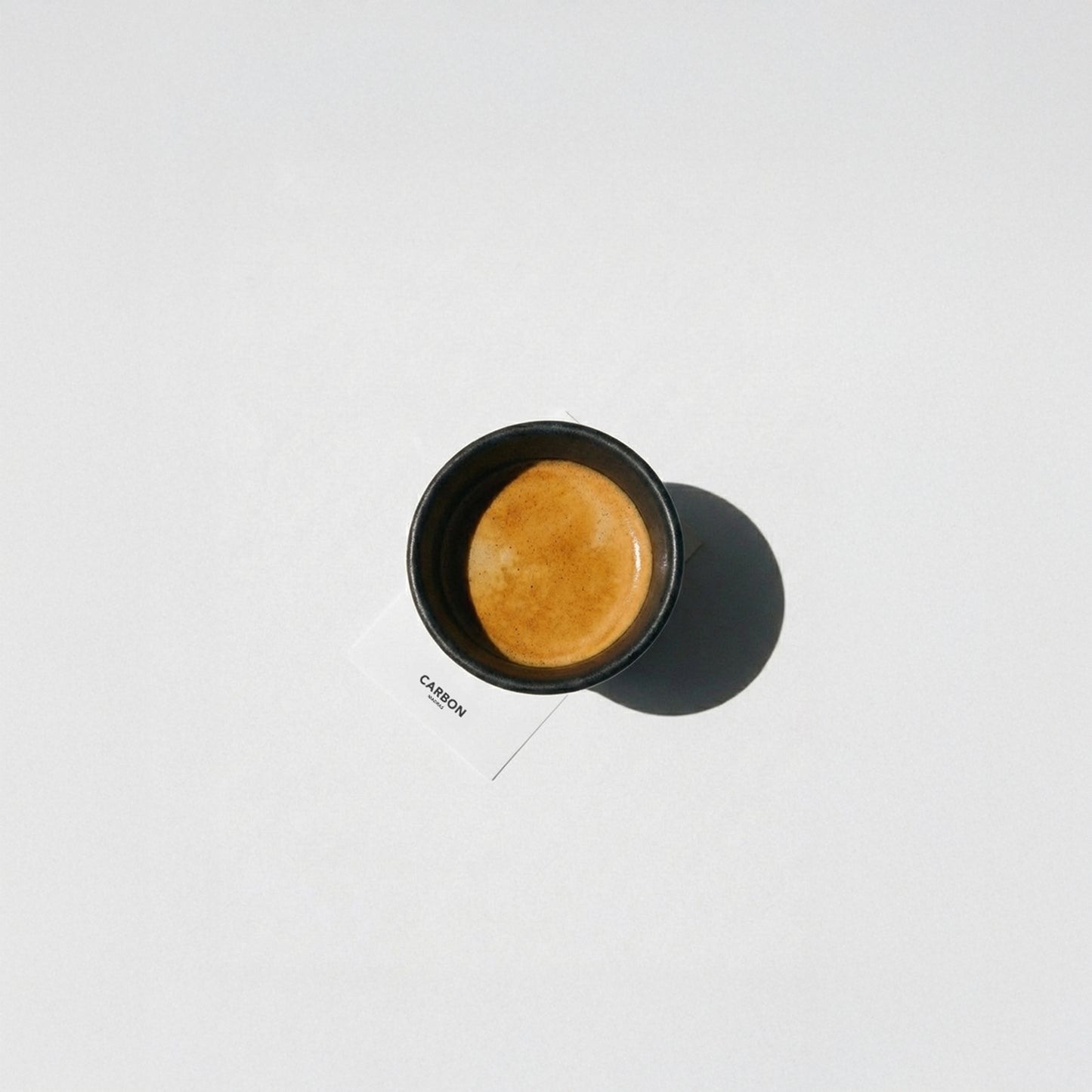 Top view of black irregular ceramic espresso cup filled with espresso crema, designer espresso cup