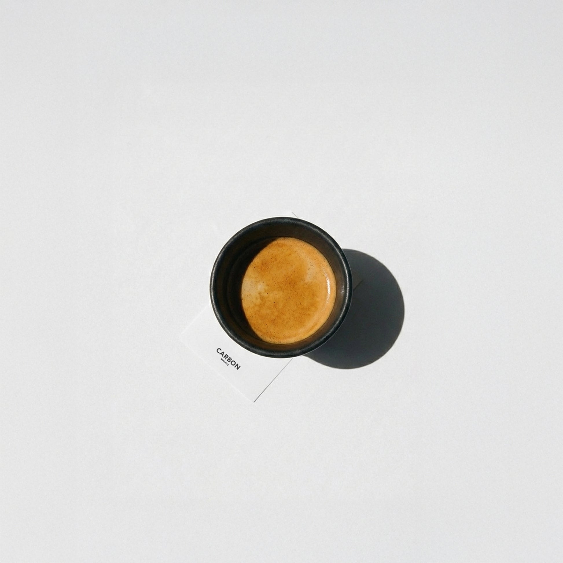 Top view of black irregular ceramic espresso cup filled with espresso crema, designer espresso cup