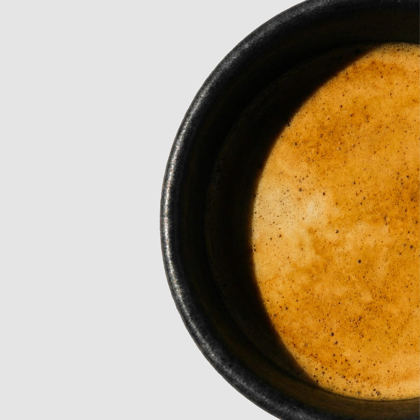 Close-up of black ceramic espresso cup showing irregular texture and handcrafted luxury design