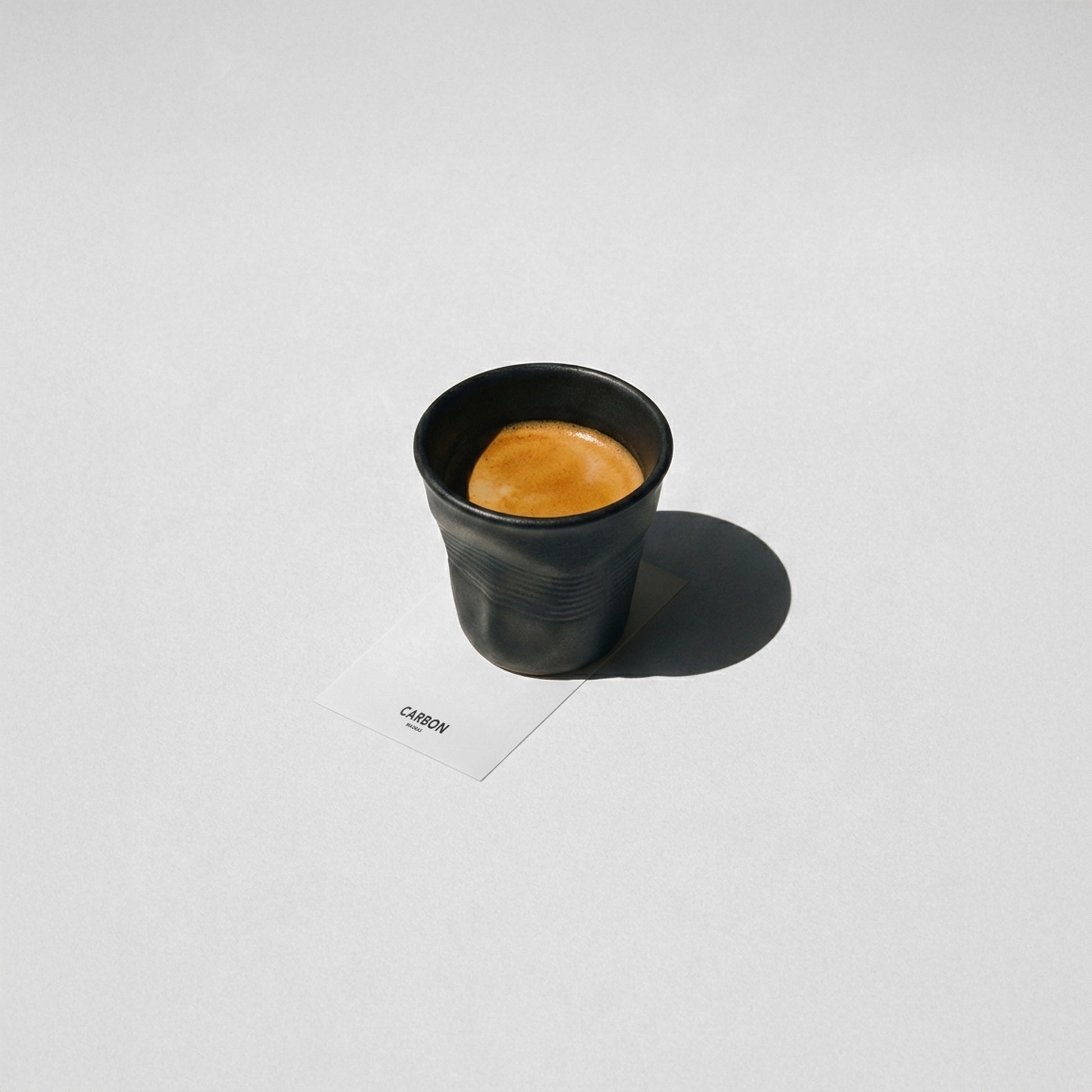 Black ceramic espresso cup with coffee, irregular crushed design luxury espresso cup by Carbon SCAR